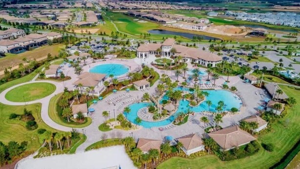 An aerial view of a resort with multiple swimming pools, landscaped areas, and residential buildings. - Family home w/private pool & hot tub near Disney (Kissimmee)