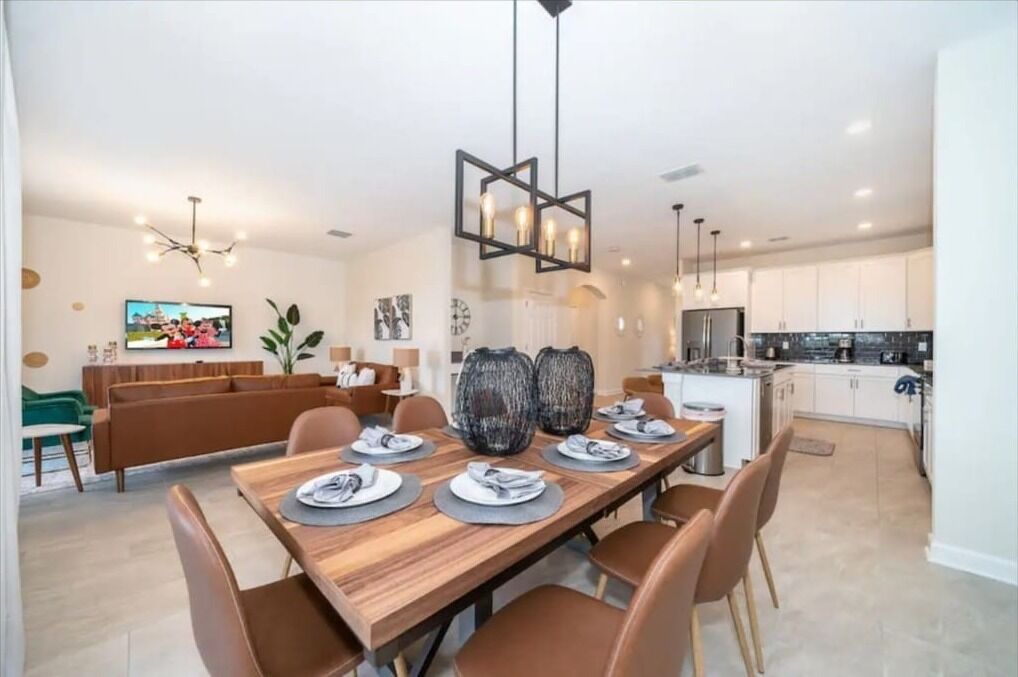 A modern dining area with a wooden table set for four, surrounded by brown chairs. A large, textured vase is placed on the table.