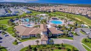 An aerial view of a resort with multiple swimming pools, a central building, and a well-maintained landscape. - Family home w/private pool & hot tub near Disney (Kissimmee)