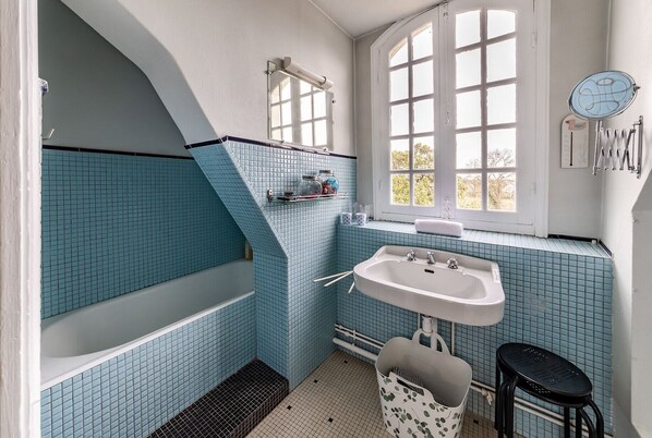 A bathroom with a bathtub, sink, and window.