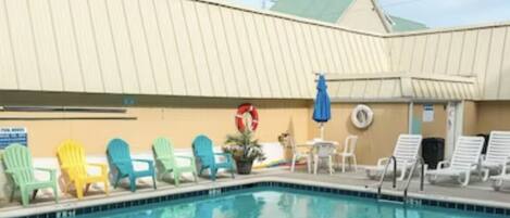 A swimming pool with lounge chairs and a lifebuoy on the wall.