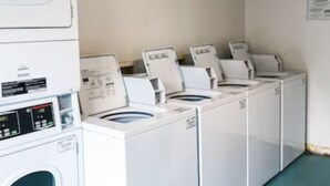 A laundry room with multiple washing machines and dryers.