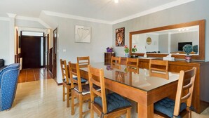 A spacious dining area with a large glass table and wooden chairs, a sofa, and a mirror above the table. - GuestReady - Comfortable Retreat in Esposende (Esposende)