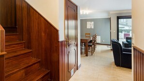 A staircase leading to a dining area with a table and chairs, a radiator, and a view through a glass door. - GuestReady - Comfortable Retreat in Esposende (Esposende)