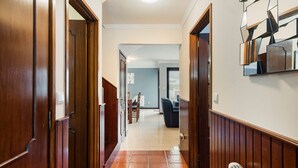 A hallway with wooden doors, a tiled floor, and a dining area in the background. - GuestReady - Comfortable Retreat in Esposende (Esposende)