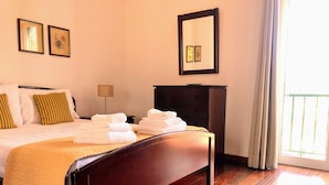 A neatly made bed with folded towels, a wooden headboard, a nightstand, and a dresser. - Costa's Old Town House (Funchal)