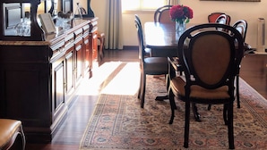 A dining area with a wooden table, chairs, a chandelier, and a painting on the wall. - Costa's Old Town House (Funchal)