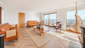A spacious living room with a large window, a sofa, a coffee table, and a hanging chair. - 5 bedroom accommodation in Berwick-Upon-Tweed (Berwick-Upon-Tweed)