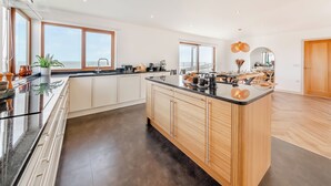 A modern kitchen with a large island, white cabinetry, and a view of the sea. - 5 bedroom accommodation in Berwick-Upon-Tweed (Berwick-Upon-Tweed)