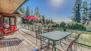 A wooden deck with outdoor furniture, a glass balustrade, and a view of trees and hills. - Water-view estate with on-site entertainment & 3 kitchens - events welcome (Clinton)