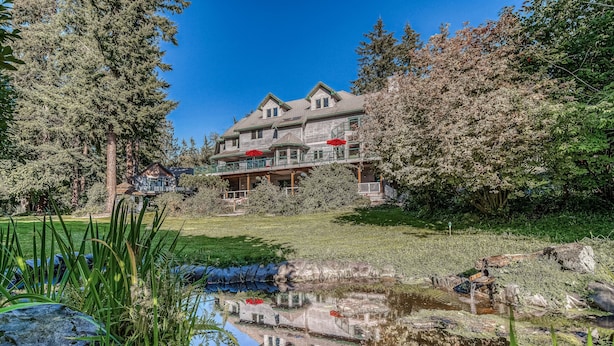 A large, two-story house with a balcony and a pond in the foreground. - Water-view estate with on-site entertainment & 3 kitchens - events welcome (Clinton)