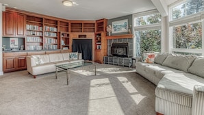 A living room with a fireplace, bookshelves, a sofa, and a coffee table. - Water-view estate with on-site entertainment & 3 kitchens - events welcome (Clinton)