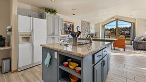 A spacious kitchen with granite countertops, a built-in oven, and a large island with a sink.