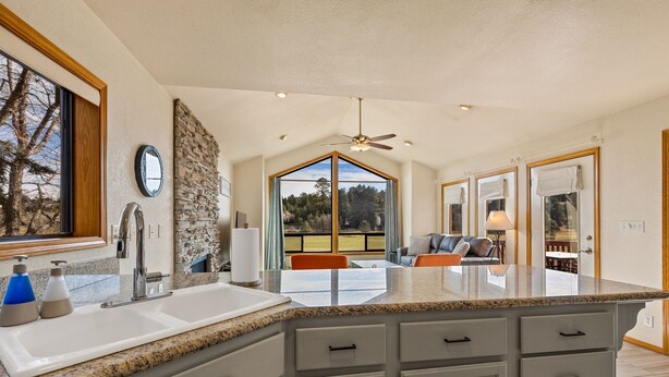 A kitchen with granite countertops, white cabinets, and a large window offering a view of the outdoors.