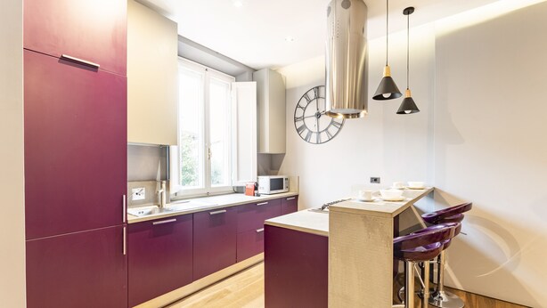 A modern kitchen with a large window, a microwave, and a clock on the wall. - Art Apartment Boboli Suite A few step from Porta Romana and Boboli's garden (Firenze)