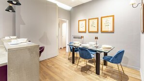A modern dining area with a glass table, blue velvet chairs, and framed botanical prints on the wall. - Art Apartment Boboli Suite A few step from Porta Romana and Boboli's garden (Firenze)