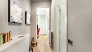 A narrow hallway with a wooden floor, a white door at the end, and framed artwork on the walls. - Art Apartment Boboli Suite A few step from Porta Romana and Boboli's garden (Firenze)