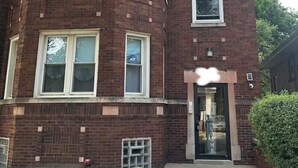 Un edificio de varios pisos de ladrillo con ventanas grandes y una puerta.