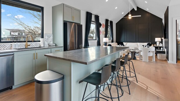 A modern kitchen with a large island, bar stools, and a view of the outside. - Music Row (Taylor's Version) Townhome (Nashville)
