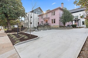 A residential street with houses, including a pink house with a front porch and steps.