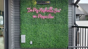 A balcony with a green artificial grass wall and a neon sign that reads "In My Nashville Era on Music Row." - Music Row (Taylor's Version) Townhome (Nashville)