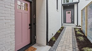 A modern building with a pink door, a number 6 sign, and a number 4 sign on the adjacent building. - Music Row (Taylor's Version) Townhome (Nashville)