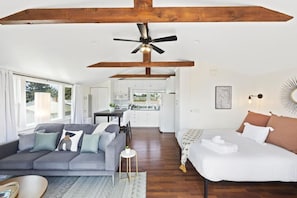 A modern interior with a sofa, a bed, a dining area, and a kitchen.