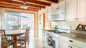 Una cucina con mobili bianchi, un fornello e un forno a microonde. C'è un tavolo da pranzo con sedie.