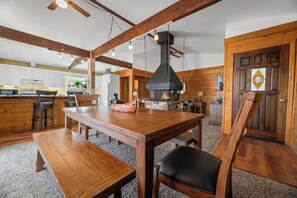 A wooden interior with a dining table, benches, and a fireplace.