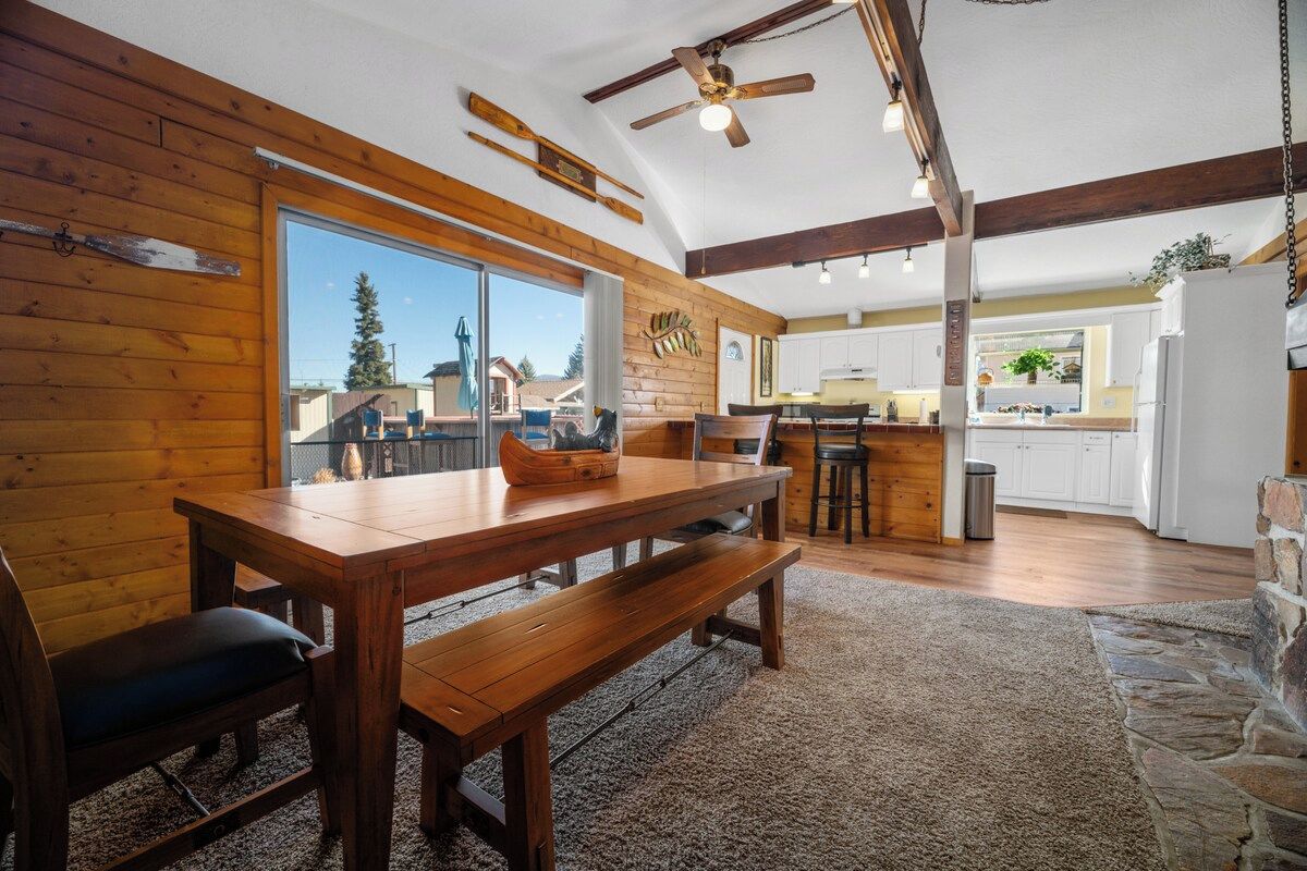 A wooden interior with a dining table, benches, and a view through a glass door.