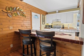 A kitchen with wooden paneling, a white door, and a bar area with two stools.