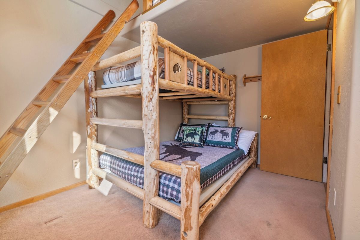 Un lit superposé avec une échelle, une porte et un luminaire.