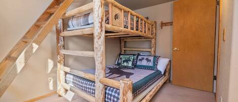 Una cama litera con escalera, puerta y lámpara.