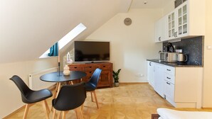Une cuisine compacte comprenant un coin repas, un téléviseur et une petite table à manger avec des chaises.