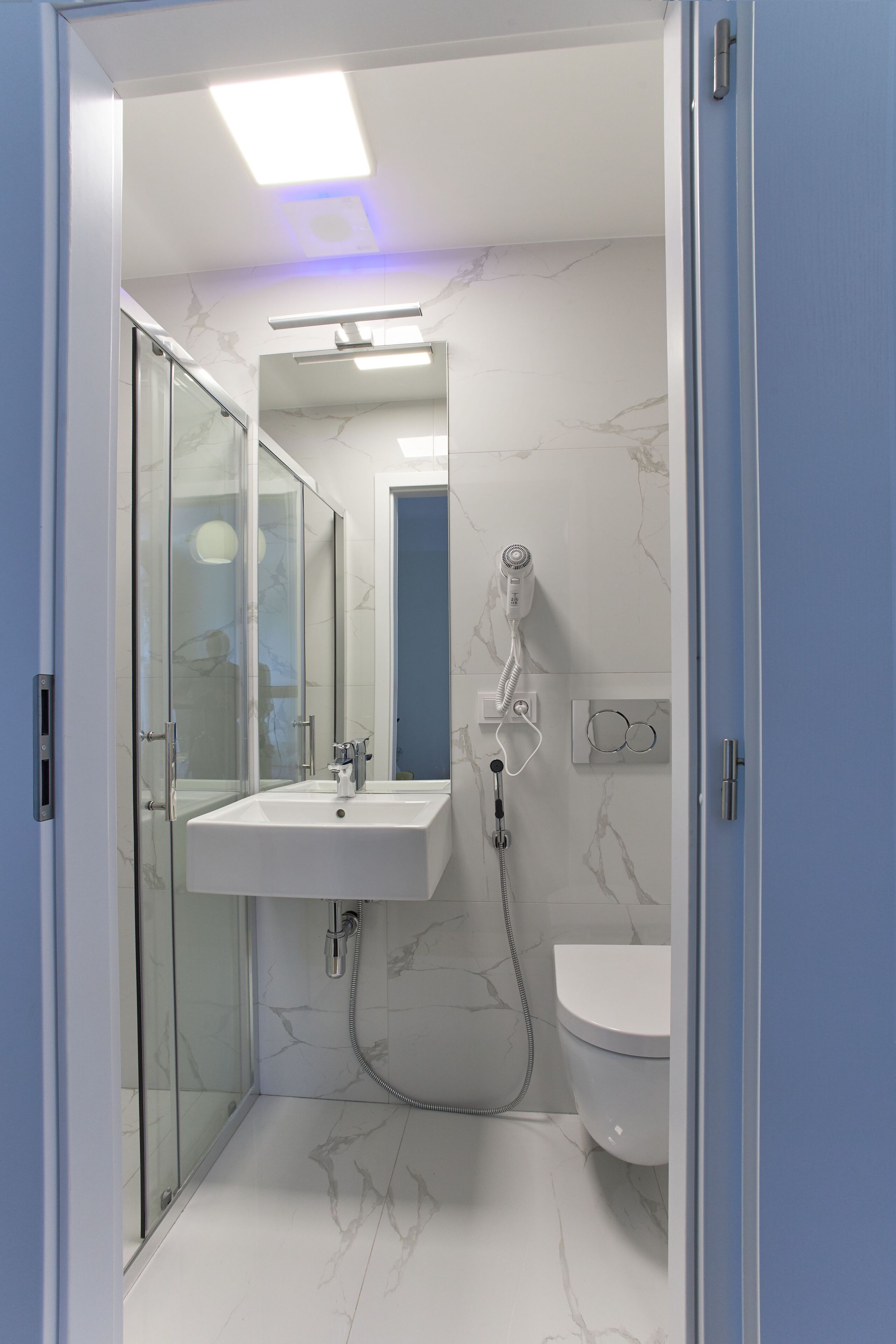 A modern bathroom with a glass shower enclosure, a white sink, and a toilet.
