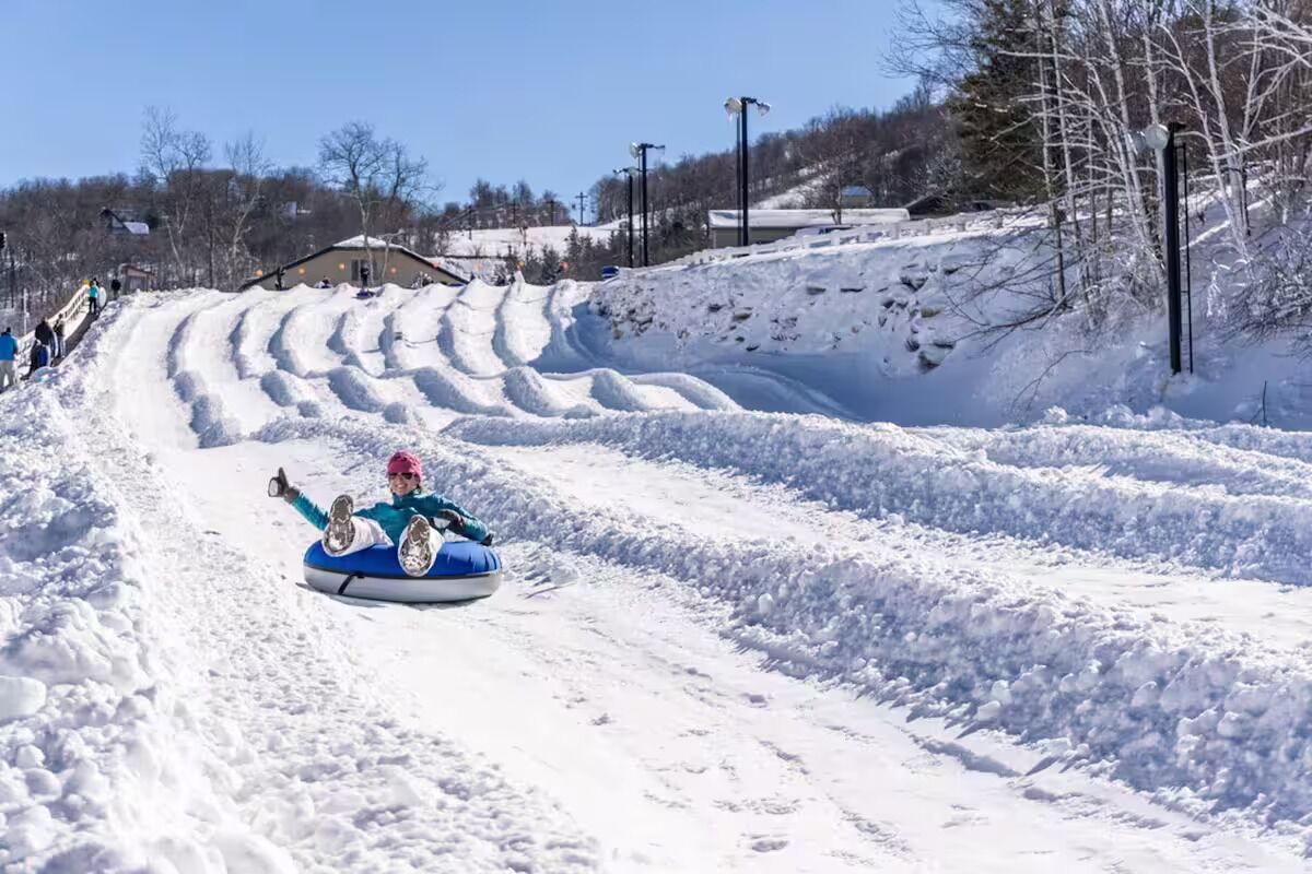 Ein mit Schnee bedeckter Hang, auf dem eine Person mit einem Schlitten gleitet.