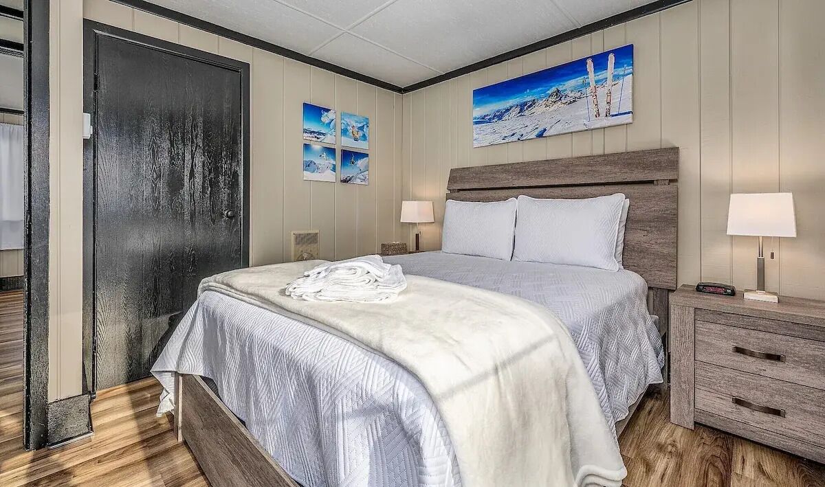 Et hotelværelse med en stor seng, et træhovedgærde, to sengeborde med lamper og en dør med udsigt til det fri.