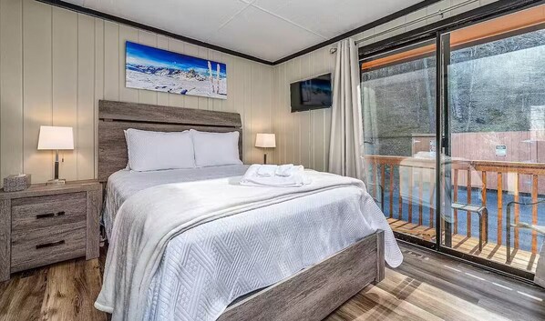 Habitación de hotel con una cama grande, dos mesitas de noche, un televisor de pantalla plana y un balcón con vistas.