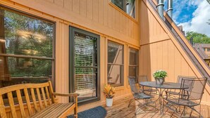 A wooden deck with a table and chairs, a bench, and a potted plant.