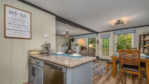 A modern kitchen with granite countertops, a dishwasher, and a dining area with a wooden table and chairs.