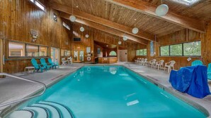 A wooden interior with a pool, chairs, and a reception area.