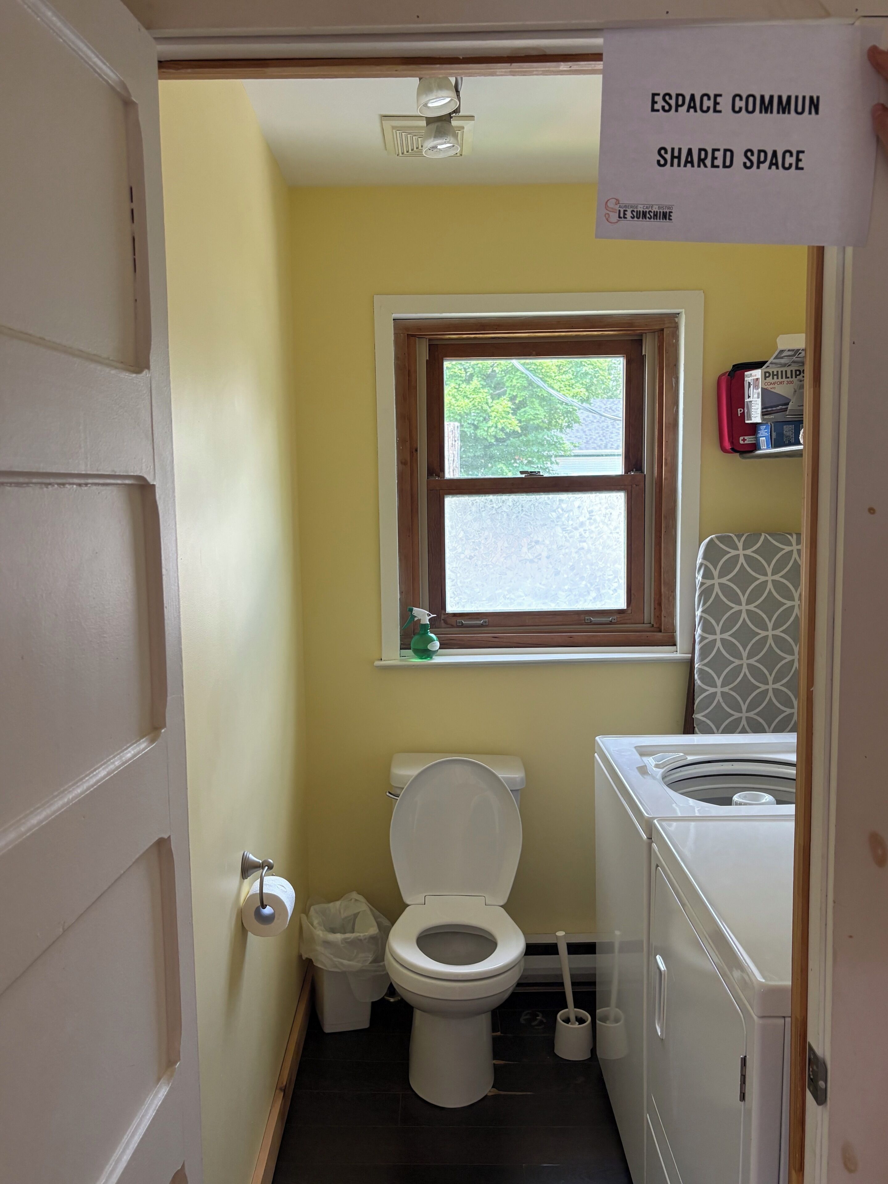 A compact bathroom with a toilet, a window, and a washing machine.