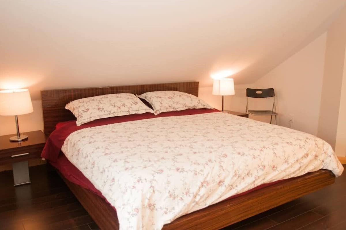 A bedroom with a wooden bed, floral bedding, two bedside lamps, and a nightstand.