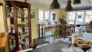 Um café acolhedor com interior de madeira, uma mesa de mármore preto e diferentes opções de assentos.