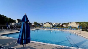 A swimming pool with lounge chairs and umbrellas, surrounded by houses. - Rehoboth Beach Home with Pool and Dedicated Workspace! (Rehoboth Beach)
