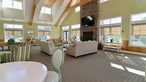 A spacious living room with high ceilings, large windows, a fireplace, and a television. - Rehoboth Beach Home with Pool and Dedicated Workspace! (Rehoboth Beach)