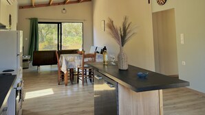Cozinha moderna com área de refeições, piso de madeira e vista pela janela grande.