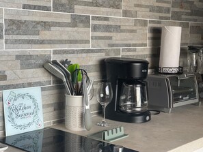 A kitchen counter with a coffee maker, toaster, and a glass of wine.