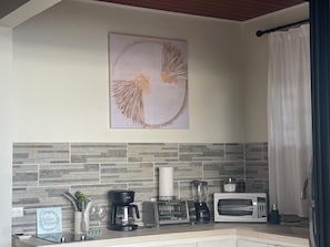 A kitchen with a stone backsplash, a coffee maker, a toaster, a blender, and a microwave. - Villa Del Mar 1. 180°, SPECTACULAR Ocean View, Gated community (Savegre de Aguirre)