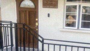 A building with a wooden door, a sign reading "The Greenidge's EST 1890", and a black metal staircase leading to the entrance.